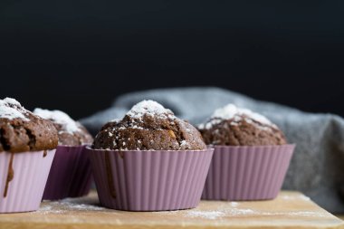 Tahta tahtaya serpiştirilmiş pudra şekeri serpiştirilmiş ev yapımı çikolatalı kekler.