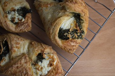 Tahta bir masanın üstünde ıspanaklı ve peynirli puf böreği.