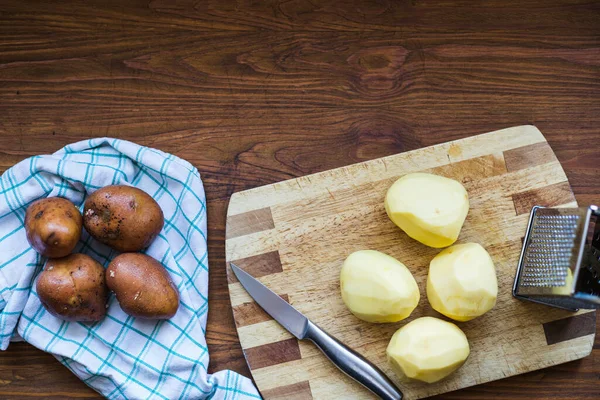 Ahşap bir masanın fotoğrafı, soyulmuş patatesler, üst manzara.