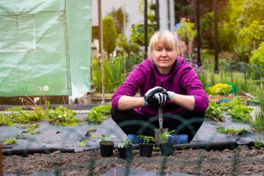 Ev bahçesinde çalışan mutlu orta yaşlı kadın. Kendi bitkilerinizi yetiştirme konsepti