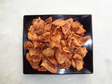 Yakın plan kurutulmuş muz krakerleri gümüş arka planlı siyah tabakta Endonezya yemeği.