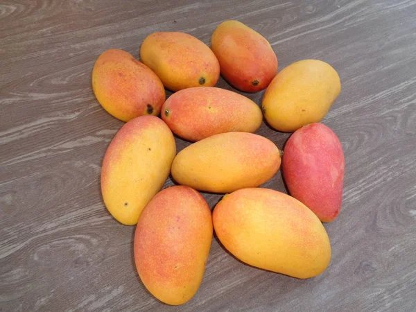 red mango, pelem podang suluh. podang mango ripe on the tree. indonesian exotic fruit with wooden brown background