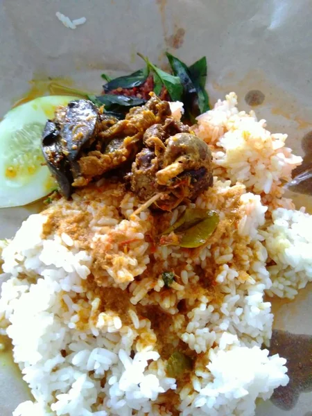 nasi bungkus (mix rice) indonesian cuisine food. rice with fried chicken heart and lungs, chili sauce (sambal), cucumber and lemon basil. the cheapest indonesian food from traditional restaurant.