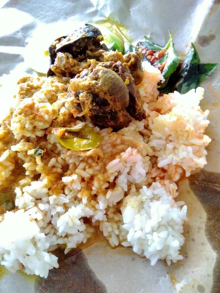 nasi bungkus (mix rice) indonesian cuisine food. rice with fried chicken heart and lungs, chili sauce (sambal), cucumber and lemon basil. the cheapest indonesian food from traditional restaurant.