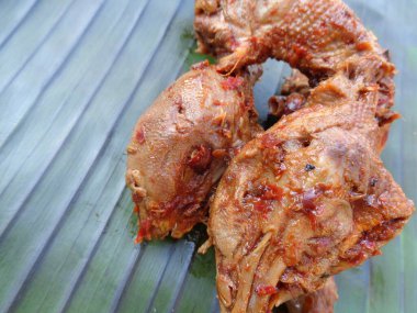 Muz yaprakları üzerinde baharatlı ızgara tavuk kafası (kepala ayam bakar pedas). Endonezya mutfağı sokak yemekleri.
