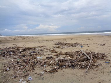 Sahildeki çöpler kirli ve dağınık gösteriyor. Kirlilik çünkü birçok plastik, ahşap ve diğerleri ziyan oluyor..