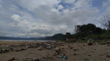 Sahildeki çöpler kirli ve dağınık gösteriyor. Kirlilik çünkü birçok plastik, ahşap ve diğerleri ziyan oluyor..