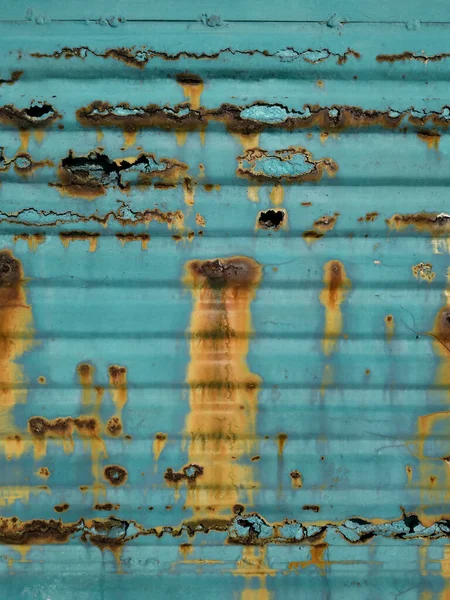 Strong metal corrosion. A rotten garage door in turquoise. Blue painted corrugated fence. Remedies for rust, metal protection, the consequences of improper maintenance of the garage and the house