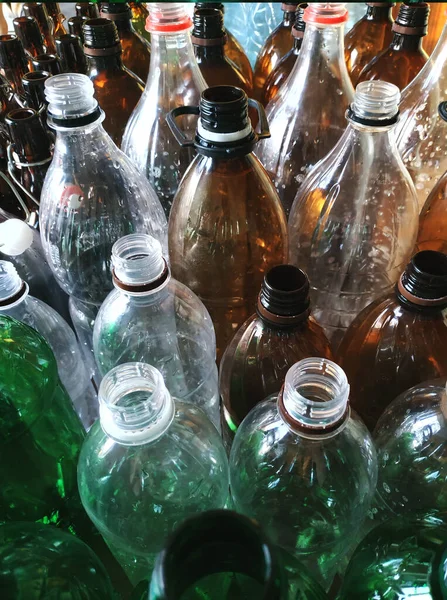 Plastic bottles without caps. Vertical photo for banner. Recycling plastic. Green, brown and transparent plastic bottles at a garbage recycling plant. Sort plastic at home and in the factory. Saving the earth