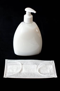 Siyah arka planda tıbbi maske ve antiseptik sabun. Hastalıklar için yüz maskesi, tek bir kişinin görüntüsü. Karantina Coronavirüs COVID-19 konsepti.