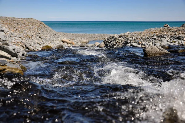 Um fluxo fresco flui para o mar. A costa do Mar de Okhotsk . — Fotografia de Stock