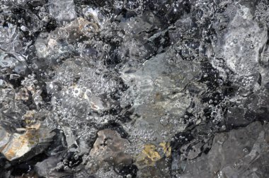 Deniz sörfü kıyı taşlarını yıkar. Soyut fotoğraf. Arkaplan fotoğrafı olarak kullanılabilir