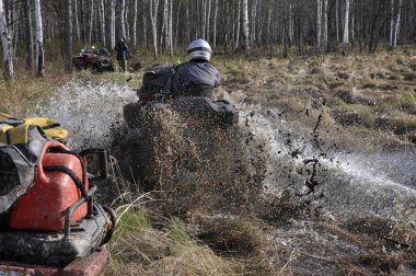 İlkbaharda ormanda birkaç Atvs su ve çamur içinde yol alır..
