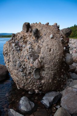 Sahilde farklı yönlere çakıl taşları fırlatılan büyük yuvarlak bir kumtaşı yığını..