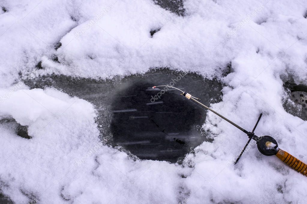 Hole in the ice and fishing rod on ice fishing