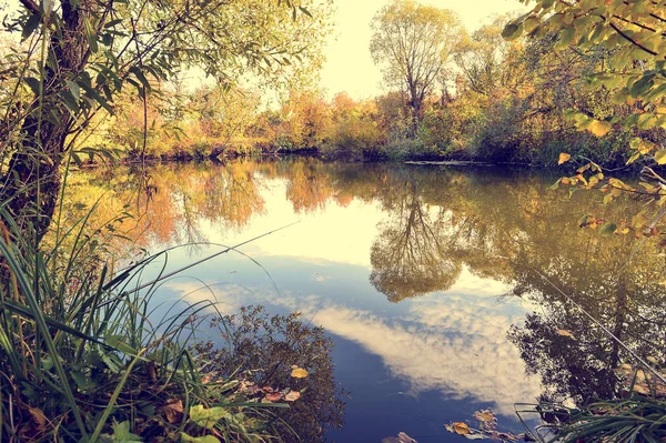 Güneşli bir günde su ve bulutlar ağaçlar ile renkli sonbahar manzara
