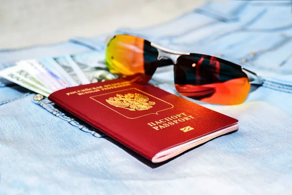 Czerwony paszport rosyjski z bonów pieniężnych i okulary na dżinsy. Koncepcja podróży. — Zdjęcie stockowe