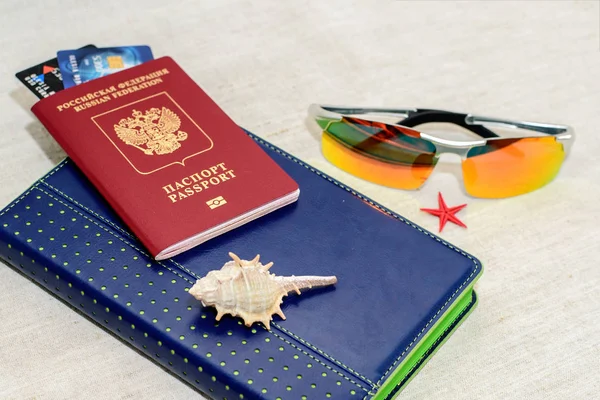 Κόκκινο ρωσικό διαβατήριο με τραπεζικές κάρτες, γυαλιά και κοχύλια. Η έννοια του ταξιδιού. — Φωτογραφία Αρχείου