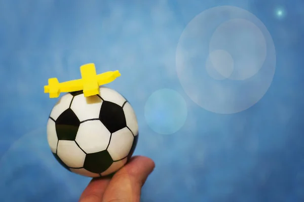 Avion jouet jaune sur un ballon de football. Le concept de voler pour le championnat de football . — Photo