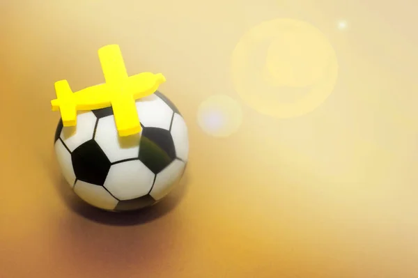 Avião de brinquedo amarelo em uma bola de futebol. O conceito de voar para o campeonato de futebol . — Fotografia de Stock