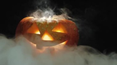 Cadılar Bayramı balkabağı kabağı kabağı kabağı oyulmuş. Masanın üzerinde beyaz dumanlı mumlar var. Duman yavaşça iniyor. Yakın çekim. 4k.