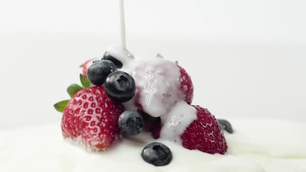 新鮮な健康食品 イチゴとブルーベリーはヨーグルトを注ぎます ヨーグルトとホイップクリームのターンでベリー 生クリームの中の新鮮な果物 有機ベリー きれいな食事 ビーガンフードコンセプト — ストック動画