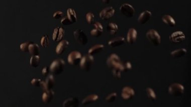 Kavrulmuş kahve çekirdekleri siyah arka planda patladıktan sonra uçar. Uçan taze kahve çekirdekleri. Yavaş Hareket.