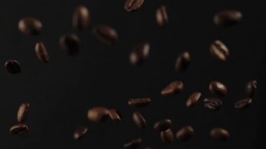 Kavrulmuş kahve çekirdekleri siyah arka planda patladıktan sonra uçar. Uçan taze kahve çekirdekleri. Yavaş Hareket.
