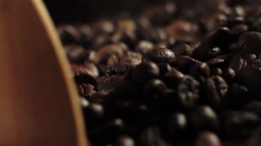 Ahşap kaşıkla kahve çekirdeklerini kızartan bir adam. Buhar tanelerden geliyor. Yavaş çekim.
