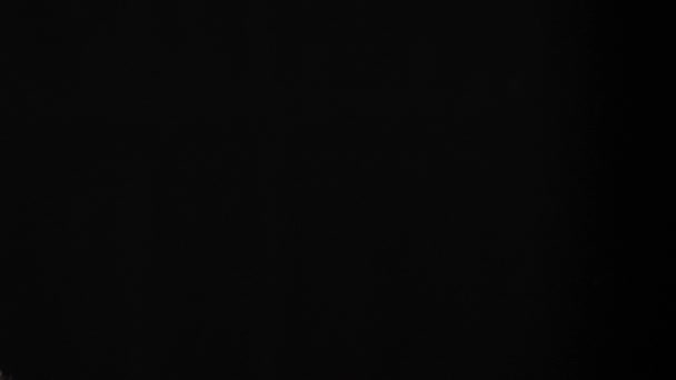 Deux tas torréfiés de grains de café sont projetés l'un vers l'autre sur fond noir. Des grains de café frais et parfumés. Mouvement lent .