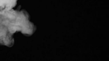Sol taraftan gerçekçi bir duman buharı etkisi var. Siyah arka planda beyaz duman yavaş çekimde. Uzayda siyah arkaplan üzerinde süzülen sis bulutu.