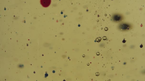 红色和透明的气泡漂浮在金液体中 透明杯子里的颜色会下降 靠近点 慢动作 — 图库视频影像
