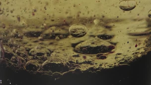 紫罗兰透明气泡漂浮在深紫色底部的金液中 透明杯子里的颜色会下降 靠近点 慢动作 — 图库视频影像