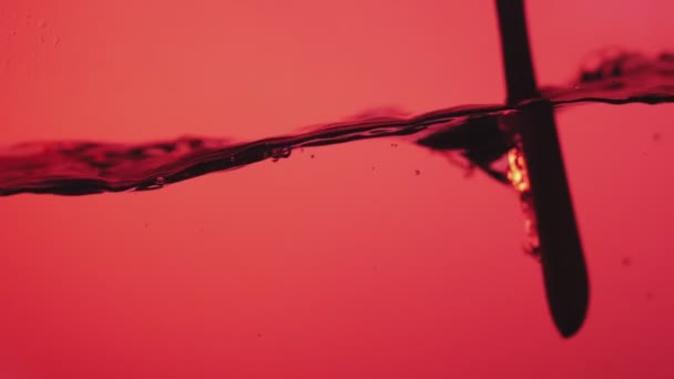 Ложка Перемішуючи Поверхню Води Червоному Тлі Красиві Бризки Води Повільному — стокове відео