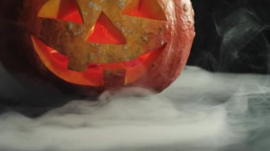 Cadılar Bayramı balkabağı kabağı kabağı kabağı oyulmuş. Masanın üzerinde beyaz dumanlı mumlar var. Ağır çekim. Yakın çekim. 4k.