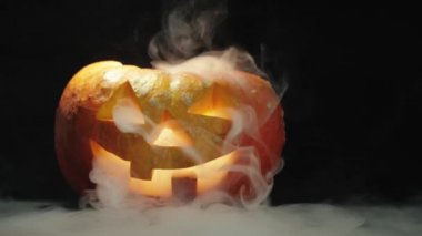 Cadılar Bayramı balkabağı kabağı kabağı kabağı oyulmuş. Masanın üzerinde beyaz dumanlı mumlar var. Işık yavaşça yanıp sönüyor. Ağır çekim. Yakın çekim. 4k.