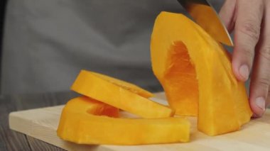 Kremalı balkabağı çorbası. Sağlıklı yiyecekler. Şef taze bir portakal kabağını ahşap bir masada dilimler. Yan görüş. 4k.