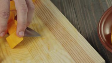Kremalı balkabağı çorbası. Sağlıklı yiyecekler. Şef, bal kabağını kahverengi bir tabağa, tahta bir masanın üzerine koyar. Kapatın. İzleme sistemi. 4k.