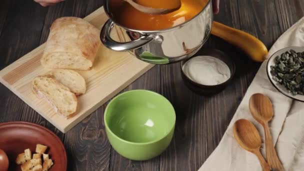 Soupe crémeuse à la citrouille. Le chef met de la soupe crémeuse à la citrouille dans un bol vert sur une table en bois décorée. 4K .