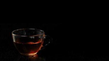 Çay seremonisi. İki buz küpü şeffaf bir fincana düşer ve siyah arka planda siyah bir masaya serpiştirilir. Modern soğuk Çin töreni.