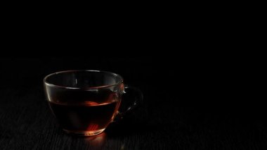 Çay seremonisi. Buz küpü şeffaf bir fincana düşer ve siyah bir masada siyah bir meyve çayı ile siyah bir zemine çarpar. Modern soğuk Çin töreni.