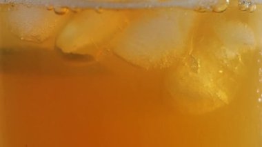 Çay seremonisi. Buz küpleri, kireç dilimleri ve parlak arka planda duran nane şekerleriyle şeffaf bir bardakta kabarcıklar beliriyor. Modern soğuk Çin töreni. Kapatın. Yan görünüm