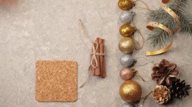 Yeni yıl ve Noel süsü. Biraz kozalak, Noel ağacının dalları, gümüş dokuda tarçın çubukları, kurdeleler ve çiçekler. El masaya bir fincan Noel çayı koyar. Üst görünüm