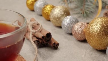 Yeni yıl ve Noel süsü. Biraz kozalak, Noel ağacının dalları, gümüş dokuda tarçın çubukları, kurdeleler ve çiçekler. El masaya bir fincan Noel çayı koyar. Kapat.