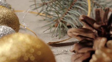 Yeni yıl ve Noel süsü. Biraz kozalak, Noel ağacının dalları, gümüş dokuda tarçın çubukları, kurdeleler ve çiçekler. El masaya bir fincan Noel çayı koyar. Kapat.