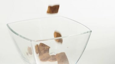 Taze sağlıklı yiyecekler. Çikolatalı gevrek pedleri beyaz arka planda şeffaf bir kare kaseye düşer. Sağlıklı kahvaltı, temiz yemek, diyet, detoks, vejetaryen, vejetaryen yemeği. Üst görünüm