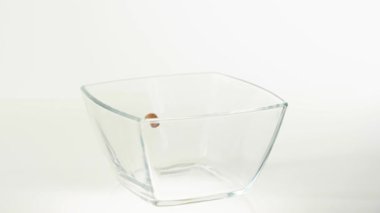 Taze sağlıklı yiyecekler. Çikolatalı gevrek topları ve sarı mısır gevrekleri beyaz arka planda şeffaf bir kare kaseye düşer. Sağlıklı kahvaltı, temiz yemek, diyet, vejetaryen yemeği. Üst görünüm