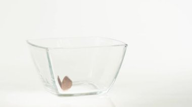 Taze sağlıklı yiyecekler. Çikolatalı gevrek taneleri beyaz arka planda şeffaf bir kare kaseye düşer. Sağlıklı kahvaltı, temiz yemek, diyet, detoks, vejetaryen, vejetaryen yemeği. Yan görünüm