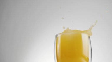 Buz küpleri su sıçramasıyla düşer ve kabarcıklar taze portakala dönüşür ya da arka planda çift duvar olan bir bardakta ananas suyu. Sağlıklı ve temiz yemek kavramı, vejetaryen yemeği. Orta çekim