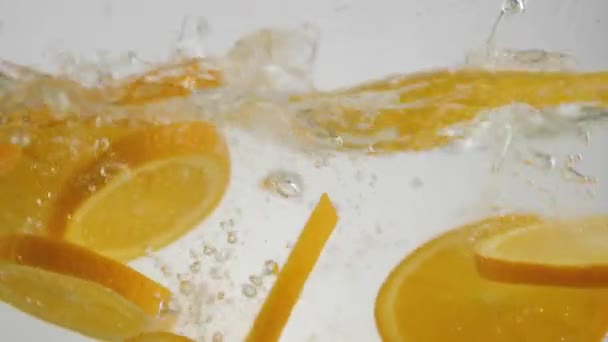 新鲜的橙片在浅色背景下掉落 溅起水花和气泡 健康和清洁的食物 素食的概念 大范围射击 — 图库视频影像